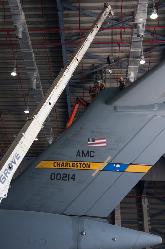 Airmen of the 8th Expeditionary Aircraft Maintenance Squadron (EAMS) and 379th Expeditionary Civil Engineer Squadron (ECES), work together using an alternative safe method to remove and replace a pitch trim actuator from the tail of a C-17 Globemaster III Dec. 16, 2018, at Al Udeid Air Base, Qatar. This is the first time a maintenance procedure like this has been done in U.S. Air Forces Central Command’s area of responsibility. Due to safety concerns, Airmen from the 8th EAMS and 379th ECES combined capabilities to ensure the aircraft could be repaired prior to returning to home station. (U.S. Air Force photo by Tech. Sgt. Christopher Hubenthal)