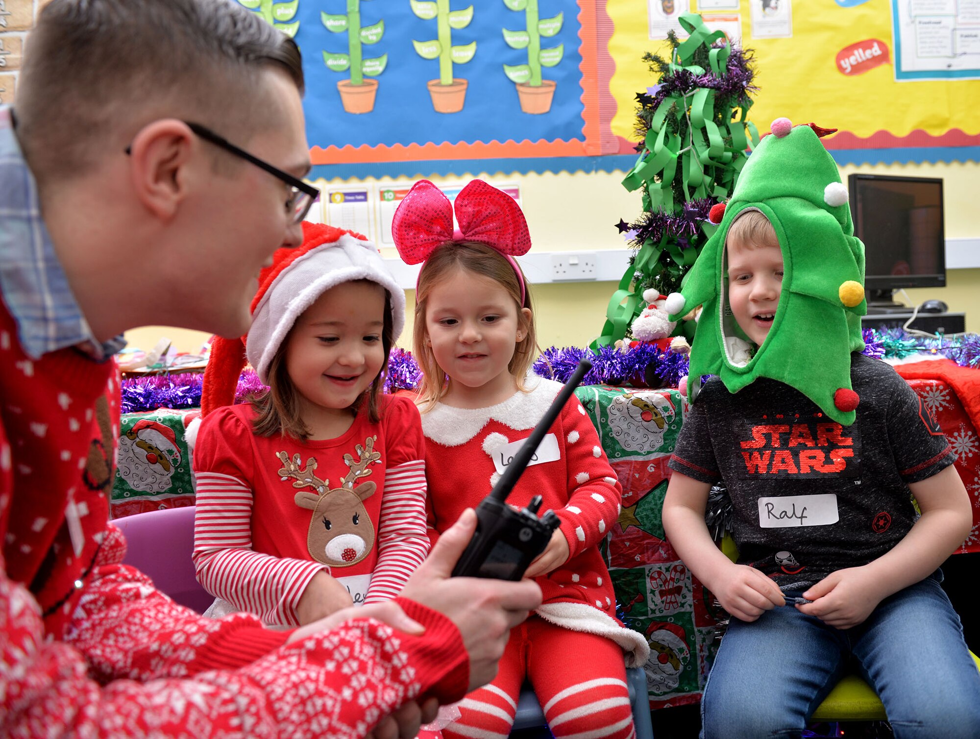 U.S. Air Force Senior Airman Roy Smith, 100th Communications Squadron radio frequency transmissions systems technician, operates a radio as children from Great Heath Academy, Mildenhall, Suffolk, talk with Santa Dec. 18, 2018. A team of three Airmen from RAF Mildenhall visited Great Heath Academy and Beck Row Primary Academy to give early years students a chance to talk to Santa about what presents they would like for Christmas. (U.S. Air Force photo by Karen Abeyasekere)