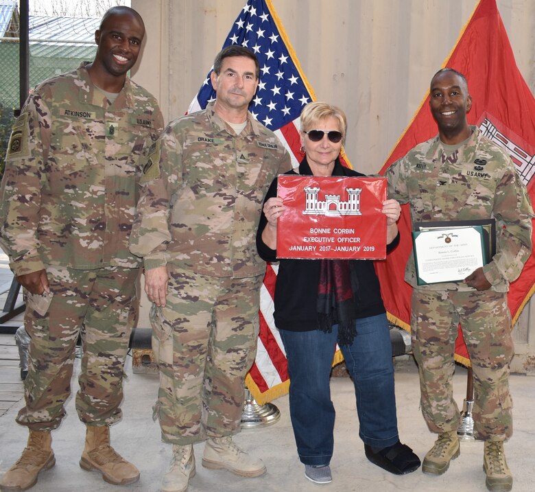 Ms. Bonnie Corbin displays not only her new footwear, but also a souvenir from members of the District and her End of Tour Awards from the Afghanistan District Command Team.