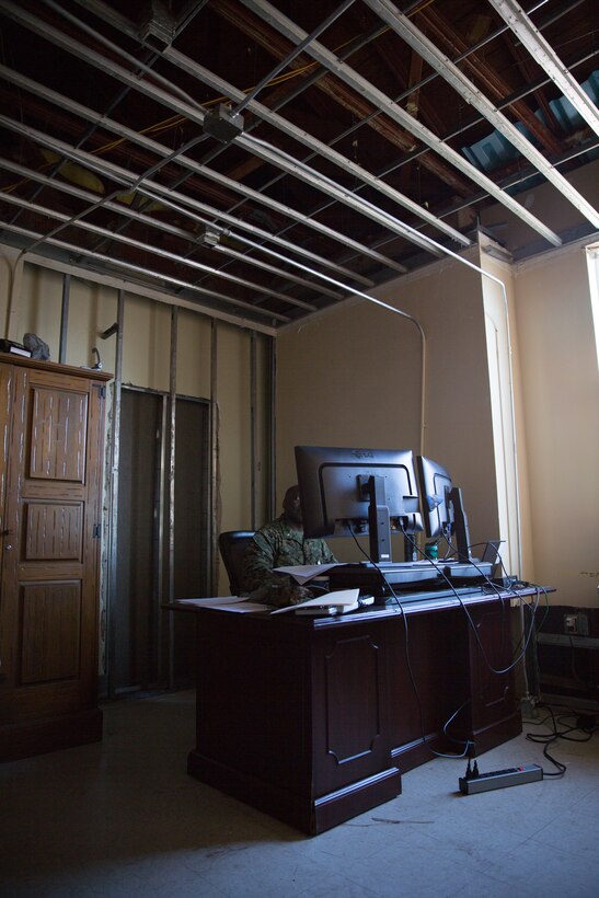A U.S. Marine continues to perform his duties inside the II Marine Expeditionary Force Headquarters building at Camp Lejeune, N.C., Dec. 11, 2018, despite working in an office with extensive hurricane damage. Contractors were required to remove most of the drywall and ceiling tiles. Three months after Hurricane Florence, damage like this can still be seen at various places throughout the building. However, Marines continue to utilize these workspaces or condense into other offices with less damage. (U.S. Marine Corps photo by Cpl. Austyn Saylor)