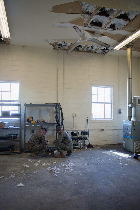 Motor transportation Marines assigned to the 24th Marine Expeditionary Unit test a vehicle battery inside their building at Camp Lejeune, N.C., Dec. 11, 2018. Ceilings inside their building continue to deteriorate due to water and storm damage. Three months after Hurricane Florence, damage like this can still be seen at various buildings on base. Despite the devastation, Marines continue to utilize these workspaces. (U.S. Marine Corps photo by Cpl. Austyn Saylor)