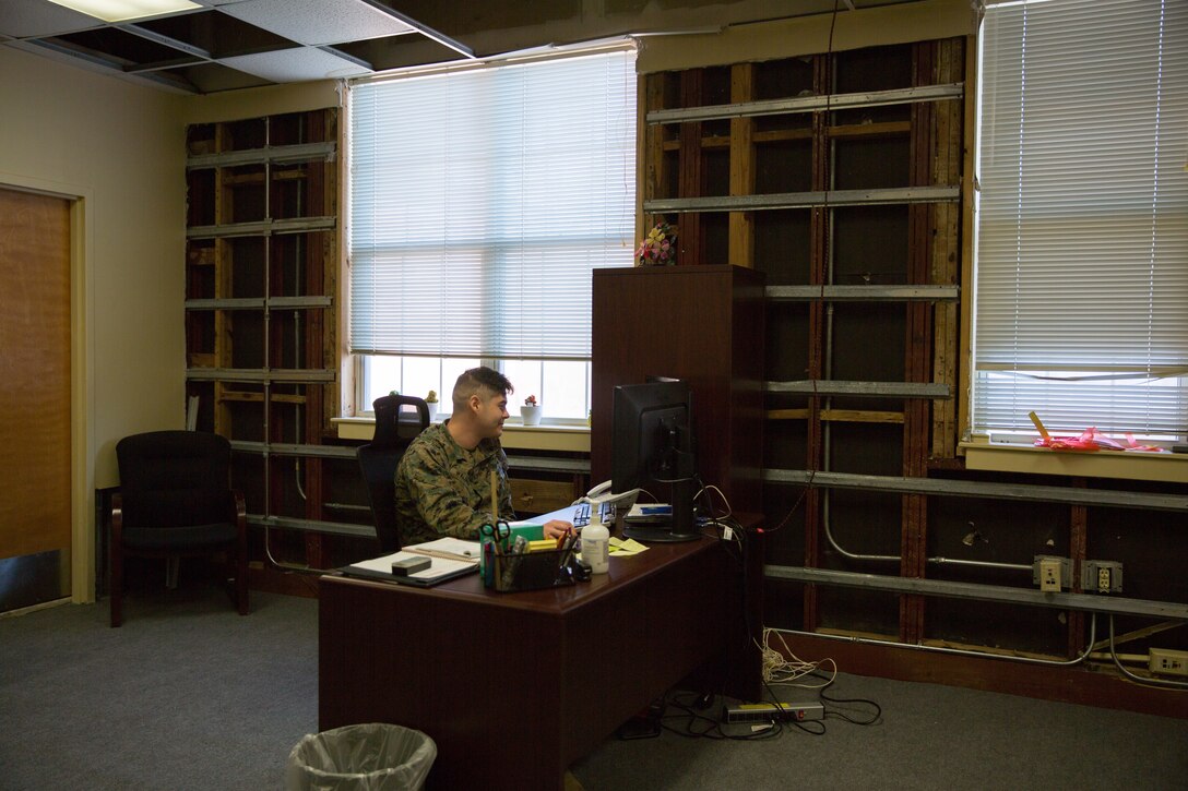 A U.S. Marine continues to perform his duties inside the II Marine Expeditionary Force Headquarters building at Camp Lejeune, N.C., Dec. 11, 2018, despite working in an office with extensive hurricane damage. Contractors were required to remove most of the drywall and ceiling tiles. Three months after Hurricane Florence, damage like this can still be seen at various places throughout the building. However, Marines continue to utilize these workspaces or condense into other offices with less damage. (U.S. Marine Corps photo by Cpl. Austyn Saylor)