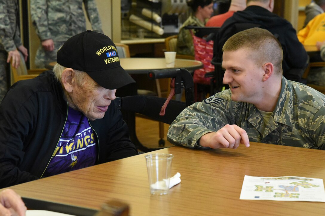 U.S. Air Force Staff Sgt. Nathan Reitan, of the 119th Wing, visits with WWII veteran Robert Olson at the North Dakota Veterans Home, Lisbon, N.D., Dec. 11, 2018.