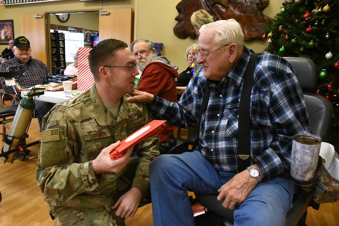 U.S. Air Force Staff Sgt. Blake Lehman, of the 119th Wing, delivers a Christmas present to U.S. Army Veteran Jim Diemert at the North Dakota Veterans Home, Lisbon, N.D., Dec. 11, 2018.