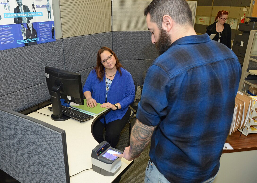 Tammi Hoover, 412th Force Support Squadron Human Resources assistant specialist, watches as a prospective job candidate places his finger on a scanner during a one-day direct hiring event at Bldg. 3000 Dec. 13. (U.S. Air Force photo by Kenji Thuloweit)