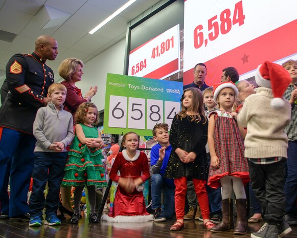 Staff Sgt. Terry Allen Davis Jr., left, 451st Combat Logistics Battalion training chief, looks on as a local business unveils the number of gifts they donated Dec. 14, 2018, on Johns Island, S.C. All of the toys were donated by individuals and businesses within the Lowcountry and given to those in the community who may have for one reason or another fallen on hard times during the holiday season. The goal of the program is to, help bring the joy of Christmas and send a message of hope to America's less fortunate children through the gift of a new toy.