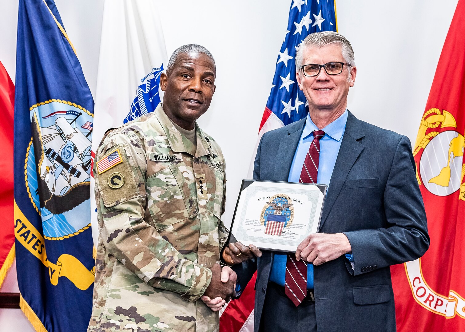 Gen. Williams shakes Ben Roberts hand while both hold certificate.