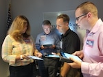 Four people standing in a semi-circle use tablets during a workshop