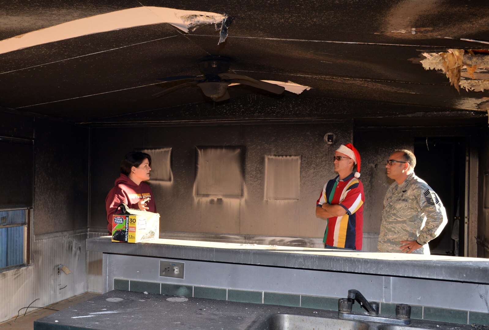 Senior Airman Krystal Donaghey, 433rd Aeromedical Evacuation Squadron, shows Master Sgt. Fernando Prendez, 433rd Airlift Wing Top-3 member, and Chief Master Sgt. Jeremy Morton, 433rd AES, the damage to her home from a house fire.