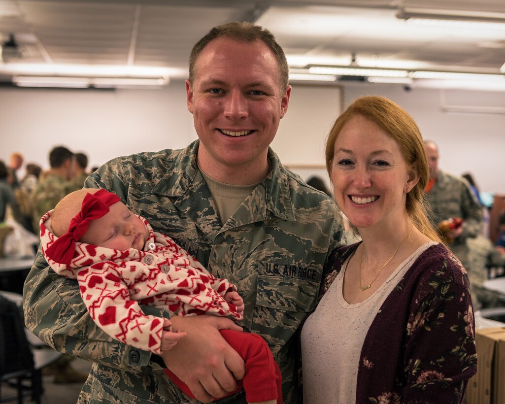 An Airman and his family pose for a photo during a holiday party.