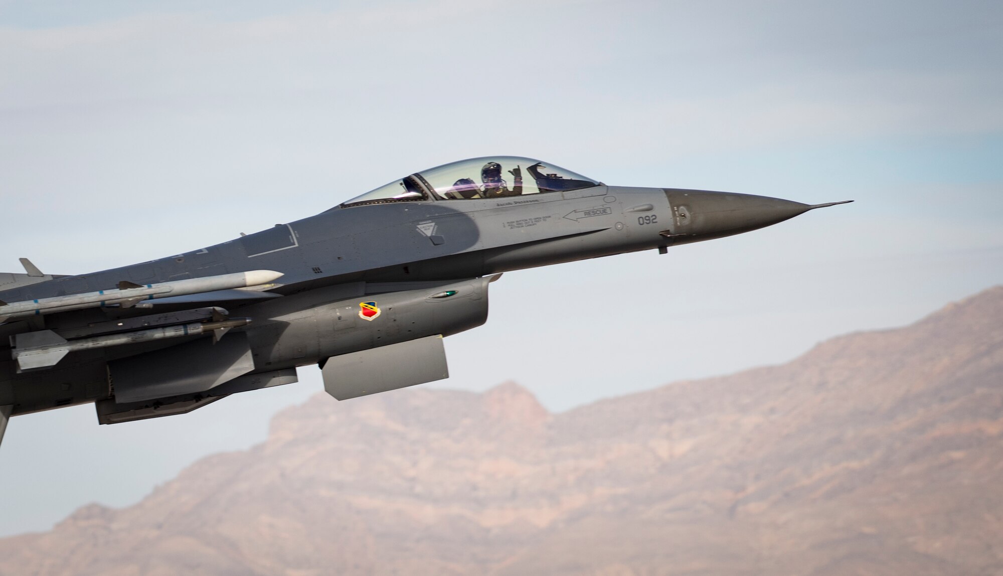 An F-16 Fighting Falcon fighting jet pilot signals after taking off from Nellis Air Force Base, Nevada Dec. 4, 2018. The F-16 is a compact, multi-role fighter aircraft. (U.S. Air Force photo by Airman 1st Class Bryan T. Guthrie)
