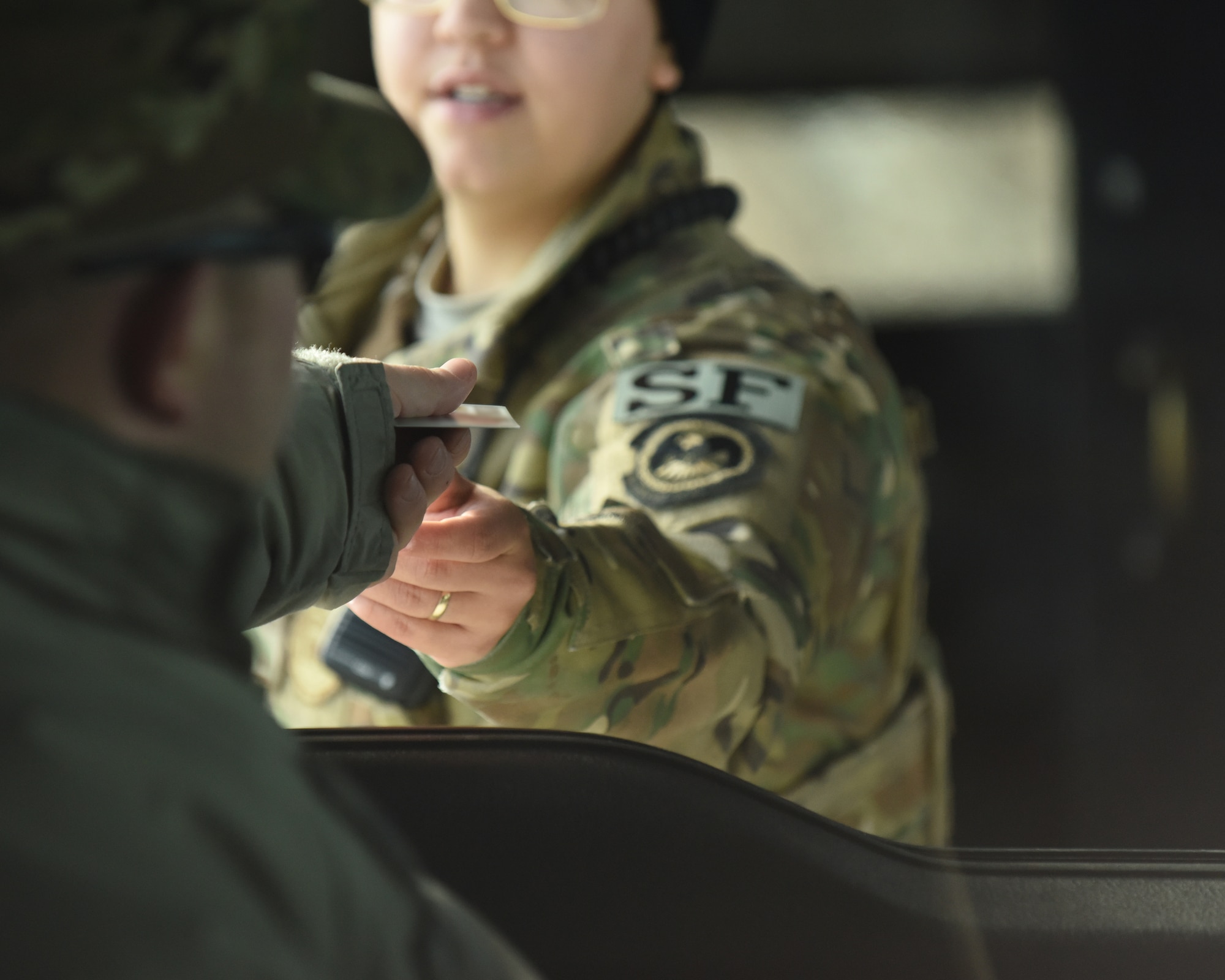 Airman 1st Class Gabriella Sepulveda, a 28th Security Forces Squadron response force member, hands an Airman back his common access card after scanning it at the gate to Ellsworth Air Force Base, S.D., Dec. 4, 2018. Each person that comes through the gate gets checked for proper authorization, correct seatbelt wear and that their vehicle has registration on the plates. (U.S. Air Force photo by 2nd Lt. Joshua Sinclair)