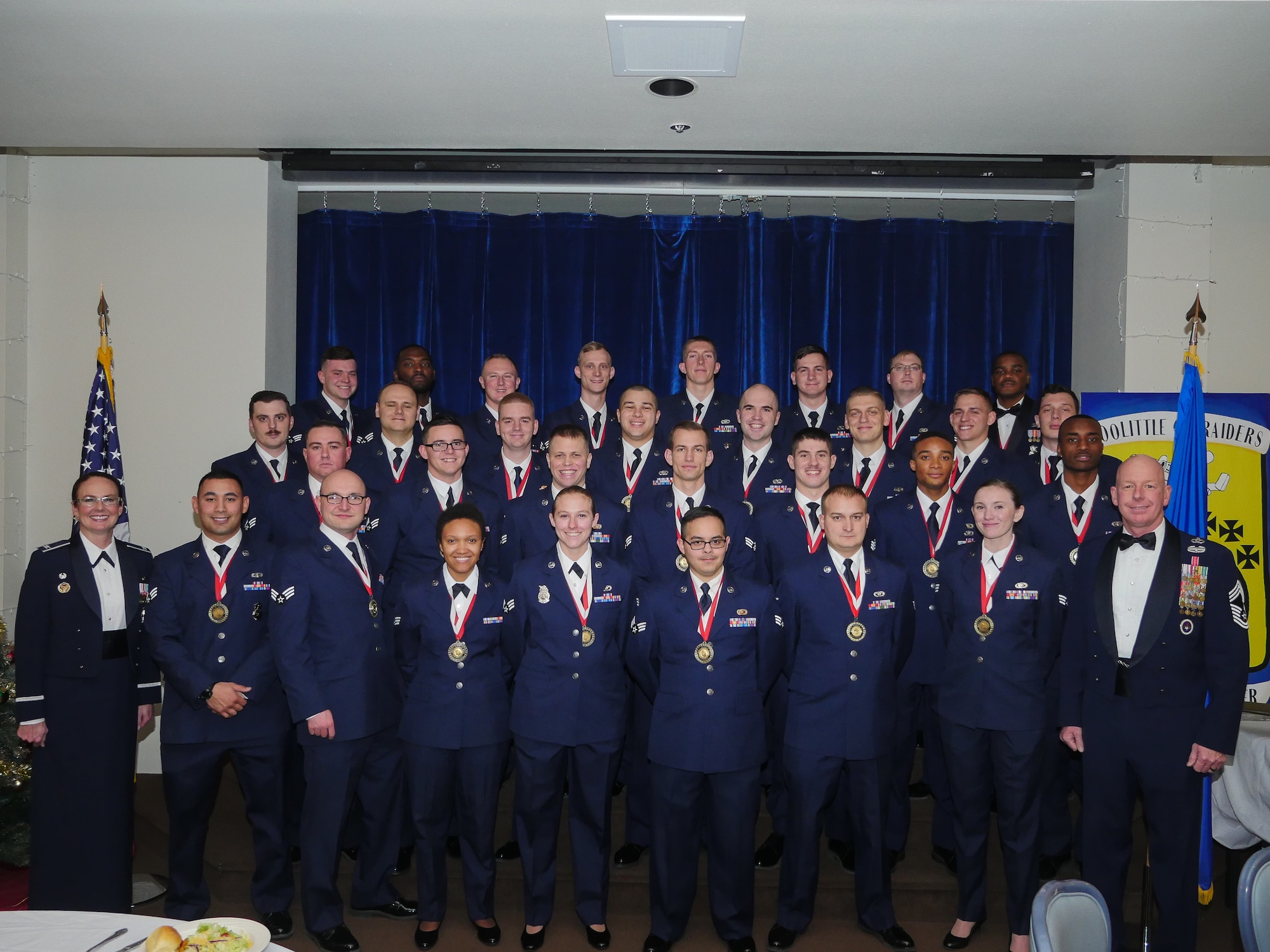 Col. Stacy Jo Huser, 90th Missile Wing commander, and Chief Master Sgt. Chris Pollock, 90th Mission Support Group superintendent, pose with the graduating Airman Leadership School Class 19-B students in the Trail's End Event Center on F.E. Warren Air Force Base, Wyo., Dec. 19, 2018. Enlisted Airmen must complete the rigorous professional military education course before supervising other Airmen.