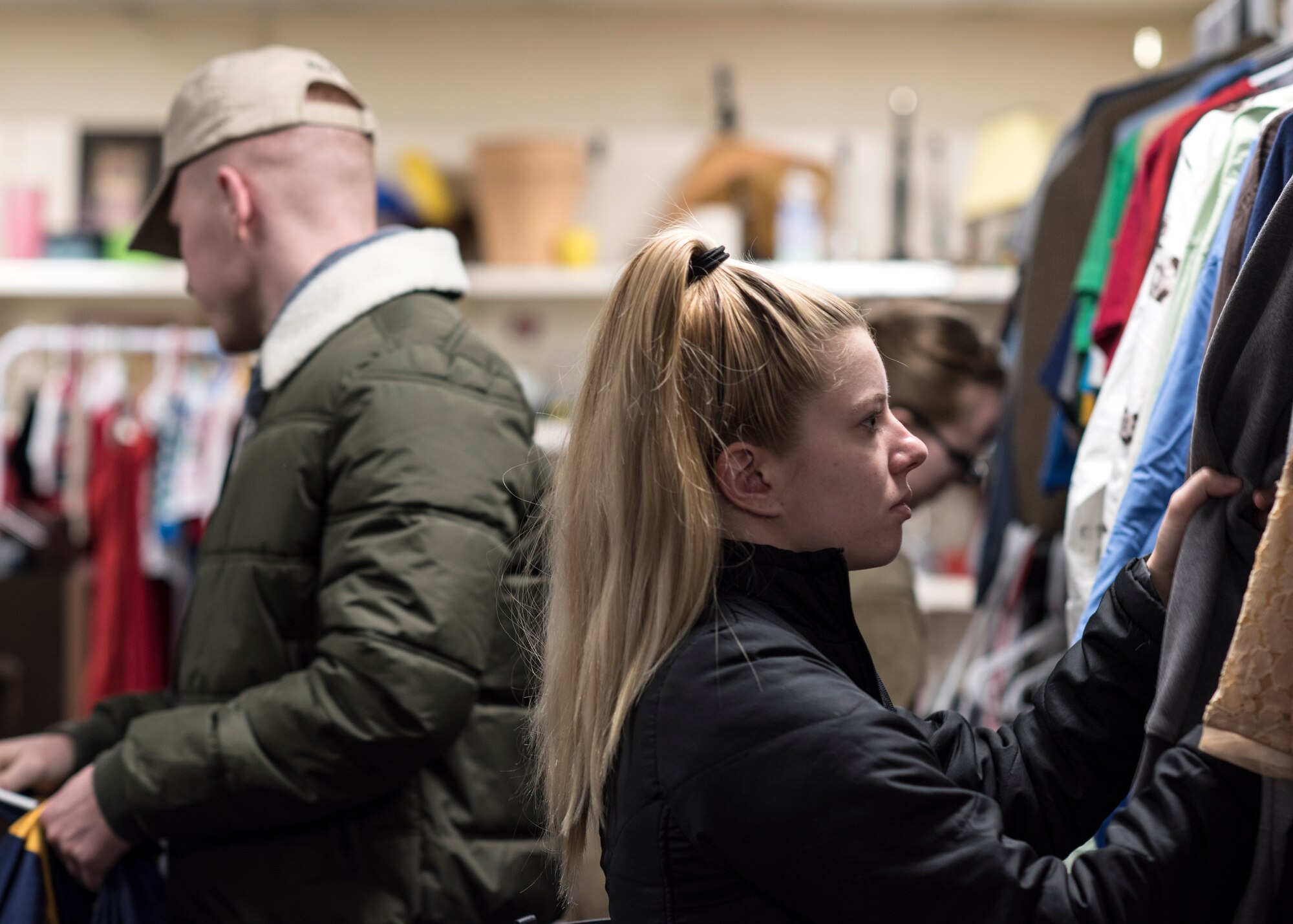 Customers at the Airman’s Attic look through clothes at Royal Air Force Lakenheath, England, Dec. 18, 2018. From uniforms and clothes to home appliances and toys, a wide variety can be found at the Airman’s Attic. (U.S. Air Force photo by Senior Airman Malcolm Mayfield)