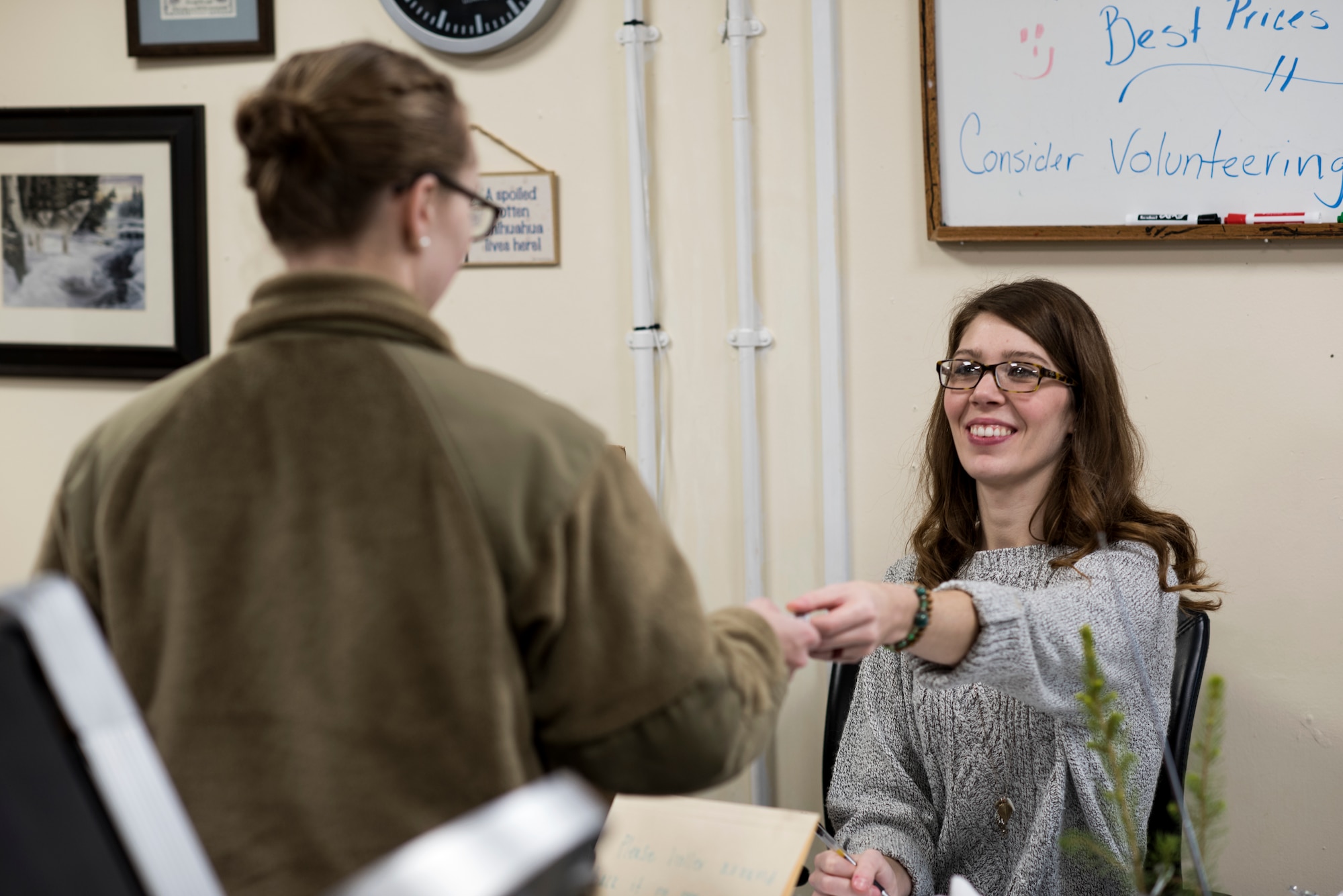 A volunteer for the Airman’s Attic returns an I.D. to a customer at Royal Air Force Lakenheath, England, Dec. 18, 2018. The Airman’s Attic servers more than 500 Airmen each month and has helped several thousand this year. (U.S. Air Force photo by Senior Airman Malcolm Mayfield)