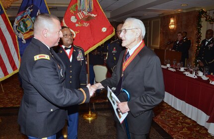 New York Army National Guard Lt. Col. Marc Lindemann, commander of the 1st Battalion, 258th Field Artillery, presents the Military Order of St. Barbara, the patron saint of the Field Artillery, to Army Pfc. Charles A. Brown, in New Windsor, N.Y., Dec. 7, 2018.  Brown served in the 258th Field Artillery during WWII and donated his archives and records of the battalion’s combat actions in 2017 to the unit and the New York State Military History Museum.