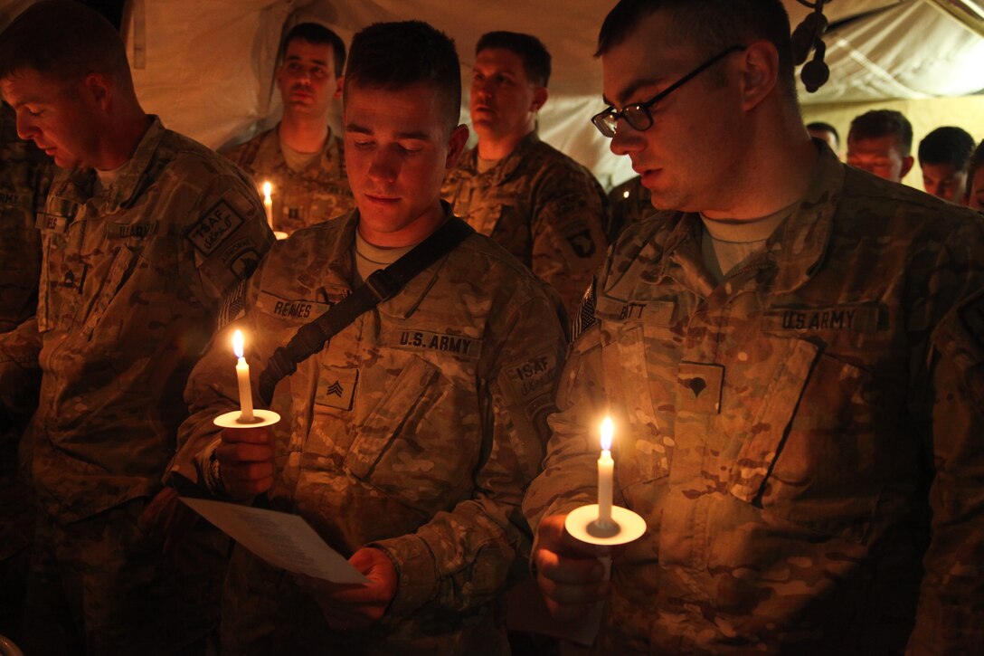 Soldiers hold lit candles.