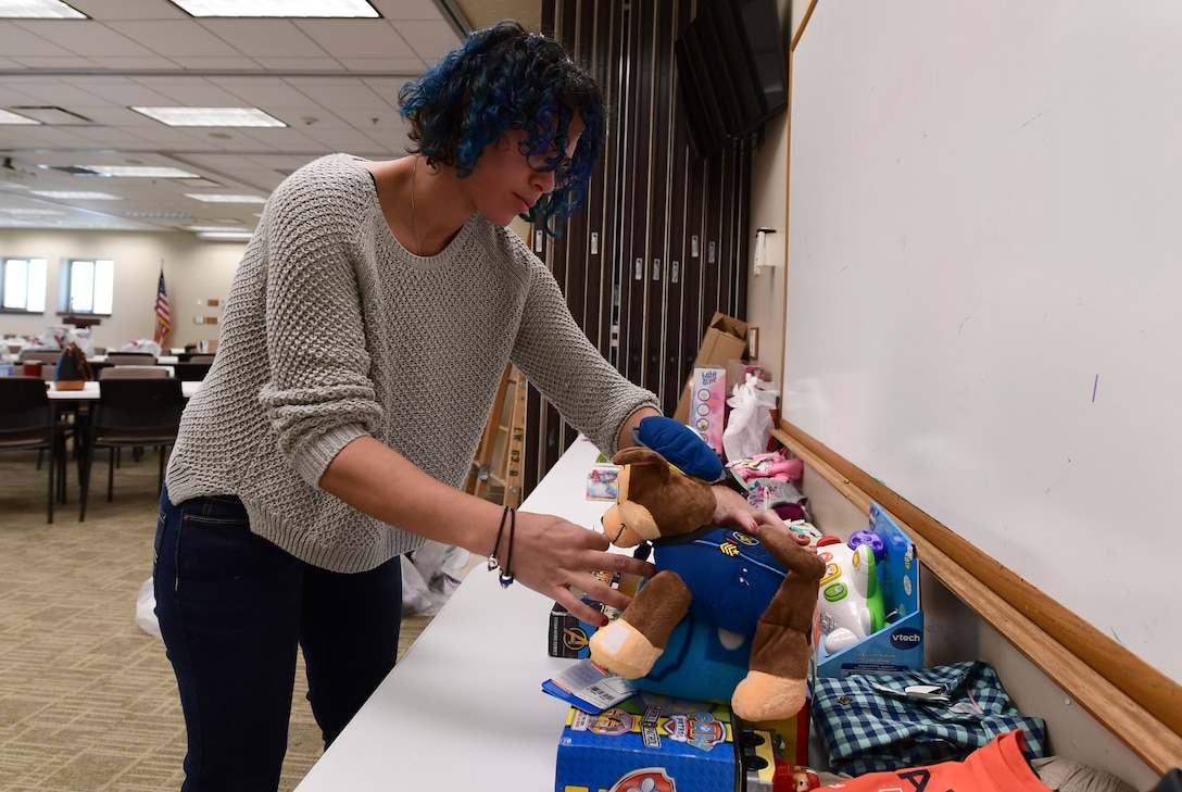 Veronica Quinones, Buckley Spouses Group member, sifts through unassigned donated gifts to find one meeting an Angel Tree recipient’s request at Buckley Air Force Base, Colorado, Dec. 19, 2018.