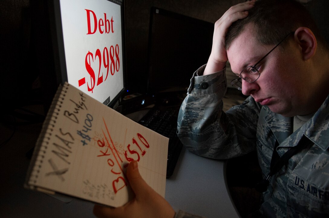 Senior Airman Samuel Earick, National Air and Space Intelligence Center photojournalist, holds his head while writing out his Christmas budget, Dec. 17. Individuals may experience the ‘holiday blues’ during this time of year and it is important that they seek help. (U.S. Air Force photo illustration by Senior Airman Michael Hunsaker)