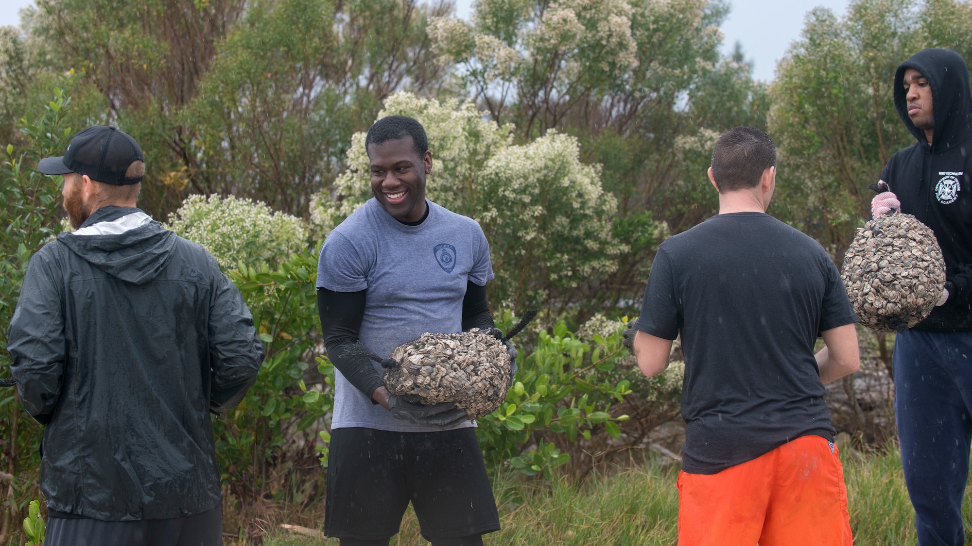 Volunteers pass mesh seashell bags in an assembly line fashion to build an oyster reef in the water at MacDill Air Force Base, Fla., Dec. 14, 2018.