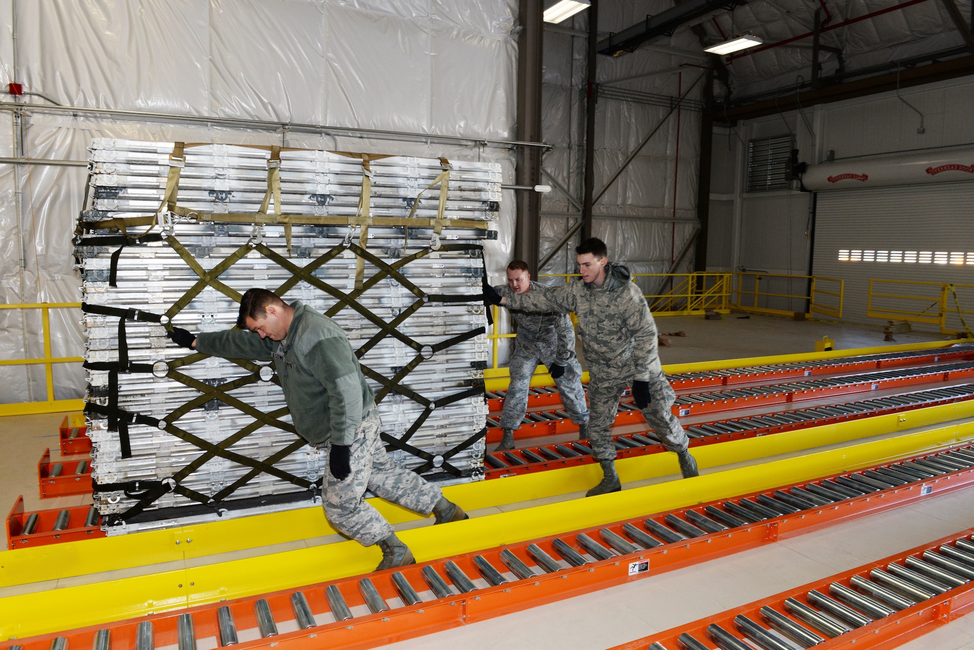 Staff Sgt. Ryan Olszewski, Senior Airman Andrew Poole and Airman 1st Class Hugh McMackin guide a pallet on the new pallet racking system, Nov. 7, 2018, at Pease Air National Guard Base, N.H. (Photo by Master Sgt. Thomas Johnson, 157th ARW Public Affairs)