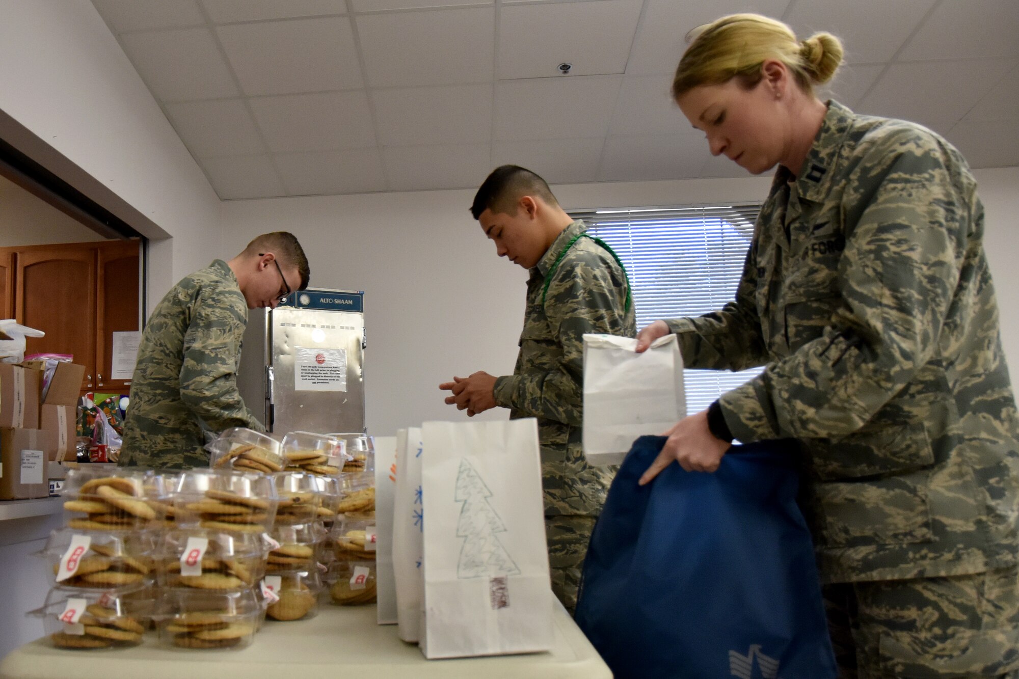 Capt. Chelsea Esenwein, 17th Training Support Squadron flight commander, stores a bag of a dozen cookies while two casual students help sort cookies. The Cookie Caper had over 40 volunteers this year. (U.S. Air Force photo by 2nd Lt. Matthew Stott/Released)