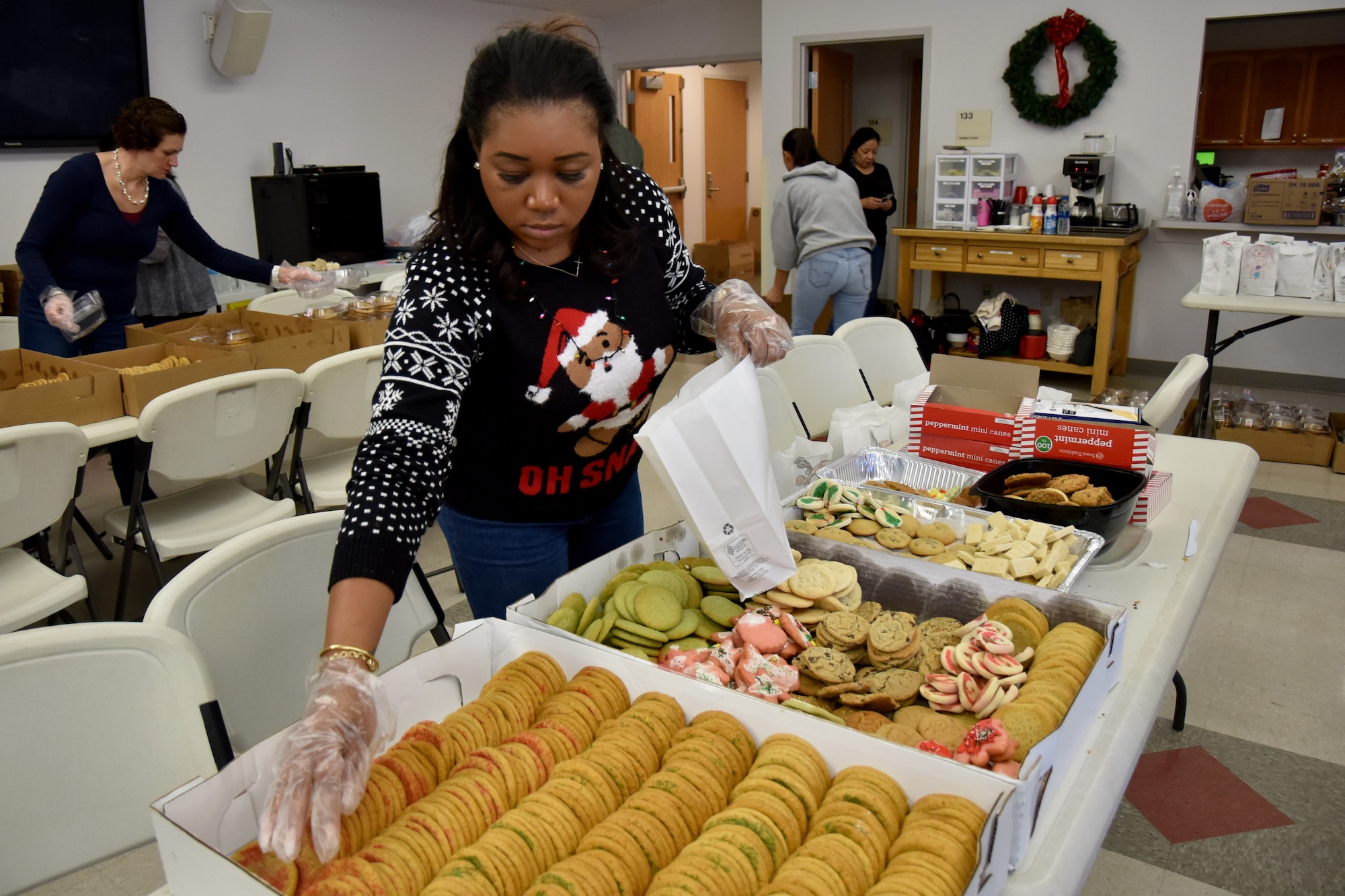 A volunteer reaches for a cookie before storing it in a bag to give to students for the holidays. The Cookie Caper packed over 18,000 cookies this year. (U.S. Air Force photo by 2nd Lt. Matthew Stott/Released)