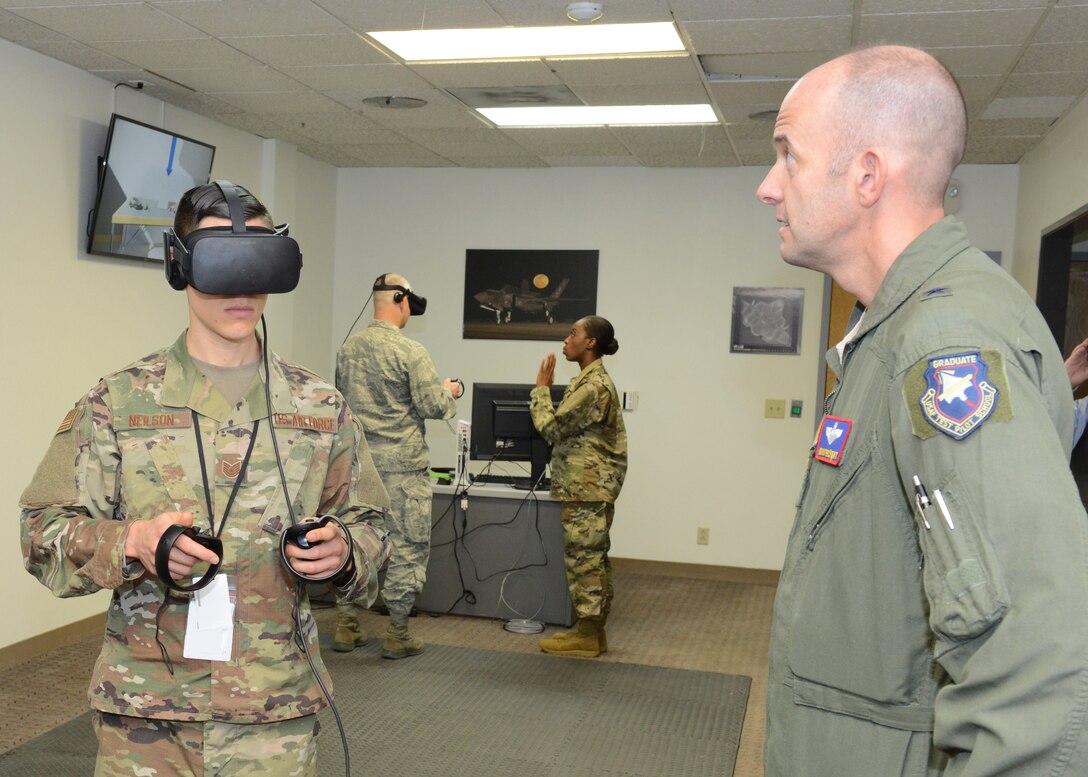 Tech. Sgt. Jeremy Neilson, 412th Aircraft Maintenance Squadron (left), prepares a virtual reality program for Brig. Gen. E. John Teichert III, 412th Test Wing commander, at the new F-35 virtual reality room Dec. 20. Neilson showed wing leadership how virtual reality can be used in conducting maintenance training for F-35 fighters. (U.S. Air Force photo by Kenji Thuloweit)