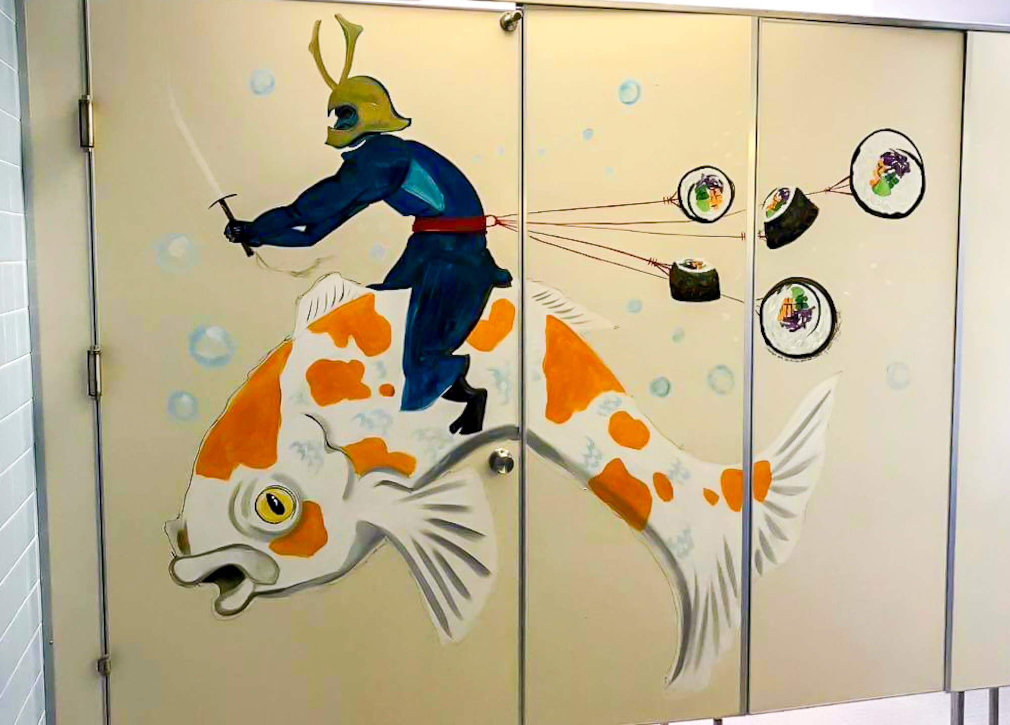 Sharon Smith, the wife of Maj. Brian Smith, a physical therapist with the 35th Medical Operations Squadron, paints a samurai in Edgren High School at Misawa Air Base, Japan, in 2018. The five sushi pieces represent her five children, while the samurai and Koi fish represent her favorite things about Japan. She shares her creativity to create morale and joy with other Team Misawa members. (Courtesy photo by Sharon Smith)