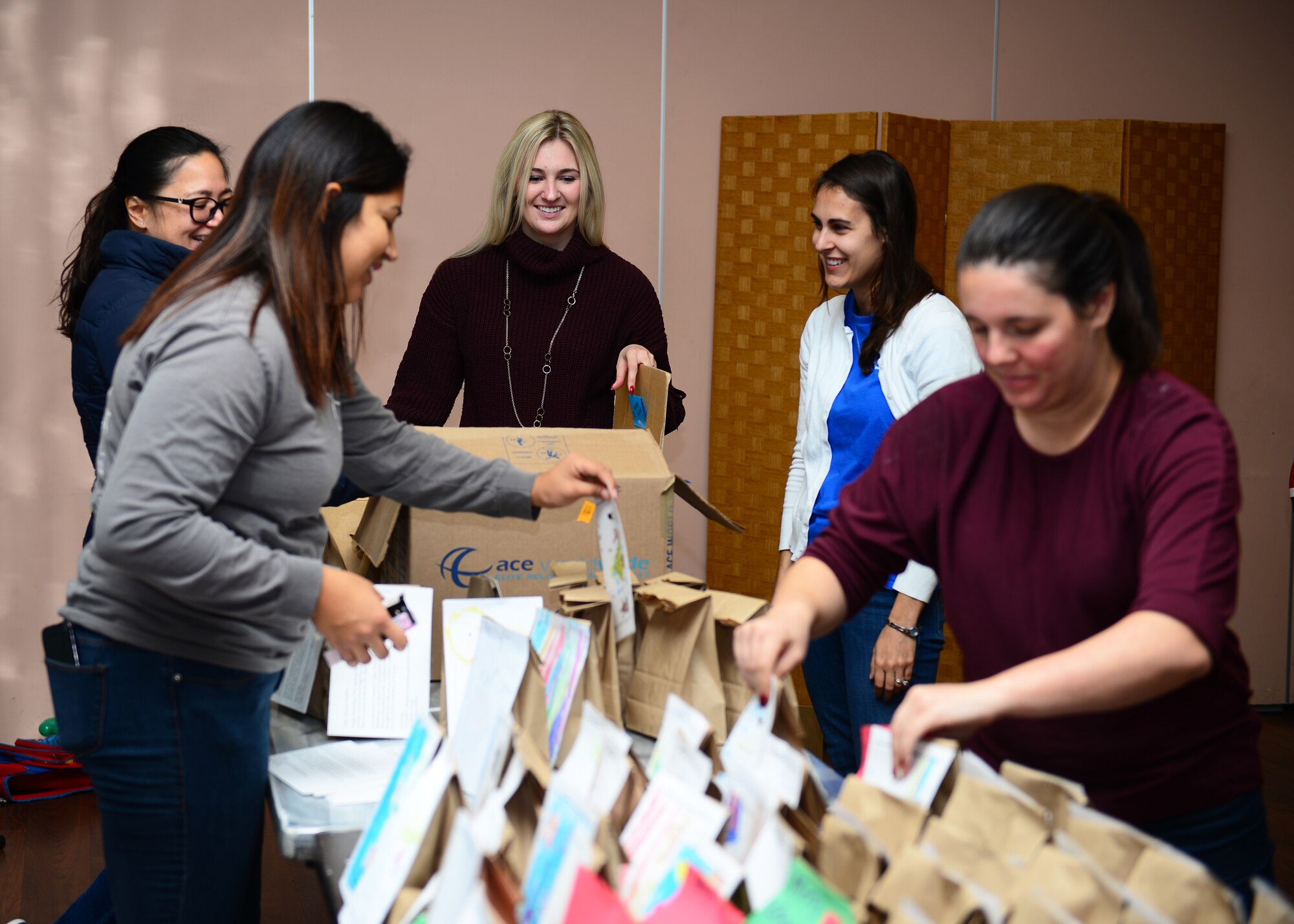 Members of the Spouses of Aviano group work together to attach holiday cards to bags of cookies during the holiday cookie drive at Aviano Air Base, Italy, Dec. 11, 2018. Approximately 25 members of the Spouses of Aviano members volunteered to help at the cookie drive.