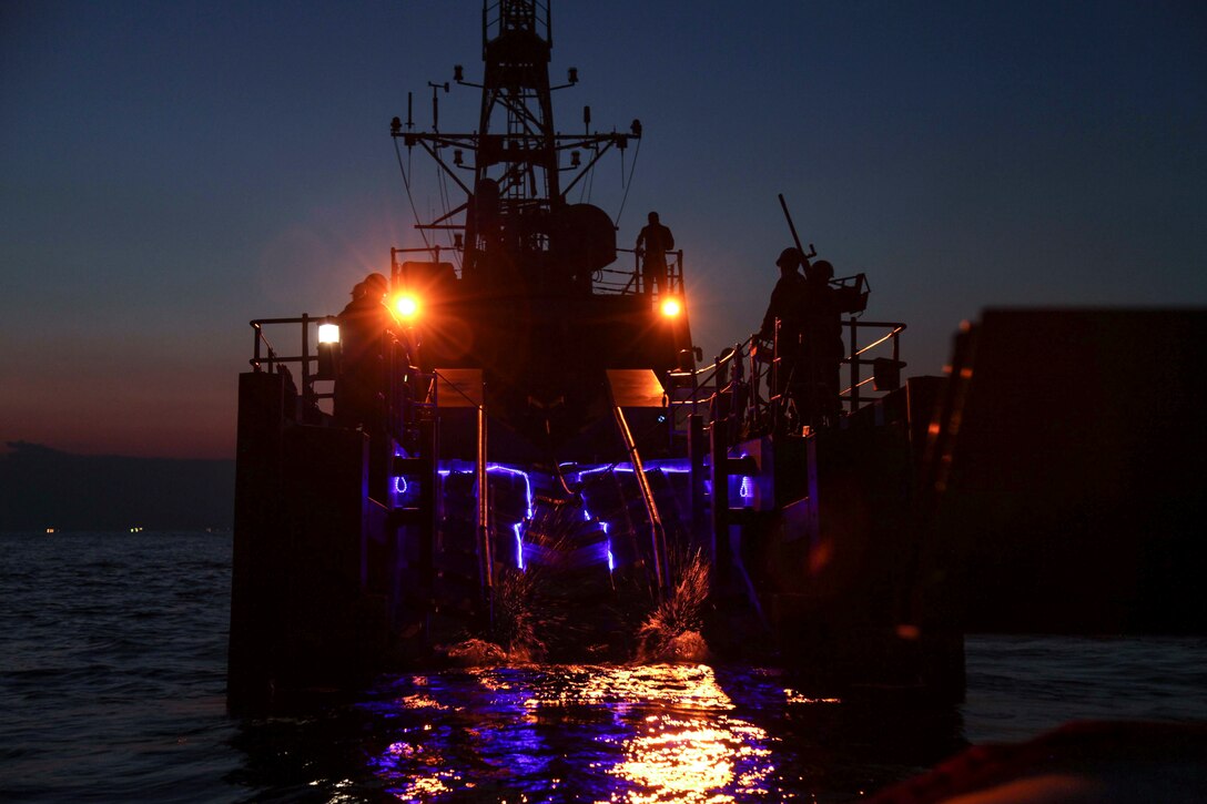 Sailors work aboard a ship at night.