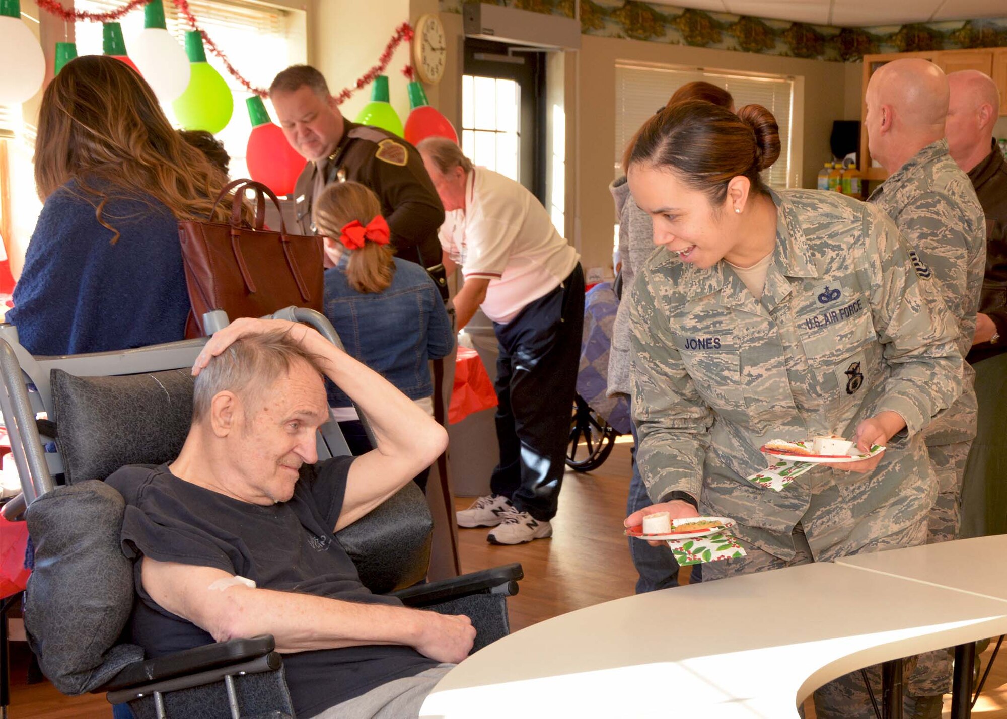 Tech. Sgt. Kathelene Jones, 507th Security Forces Squadron, serves a snack to a veteran Dec. 20, 2018, at the Norman Veterans Center in Norman, Oklahoma. 507th Air Refueling Wing Airmen visited the veterans to deliver gifts and serve snacks for the holidays. (U.S. Air Force photo by Tech. Sgt. Samantha Mathison)