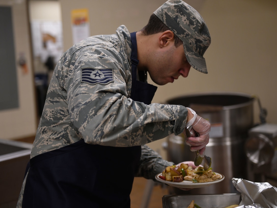 Tech. Sgt. David DeJesus, the 28th Force Support Squadron noncommissioned officer in charge of the First Term Airman Center, prepares a plate during the Chef of the Quarter cook-off competition at the Raider Café on Ellsworth Air Force Base, S.D., Dec. 18, 2018. The three teams were expected to create a meal and were judged on presentation, creativity, originality and, most importantly, taste. (U.S. Air Force photo by Airman 1st Class Christina Bennett)