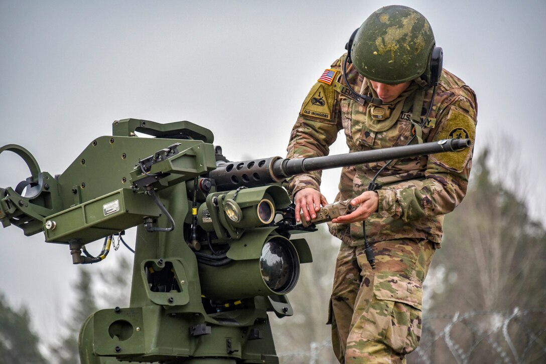 A soldier looks over a large vehicle-mounted weapon.