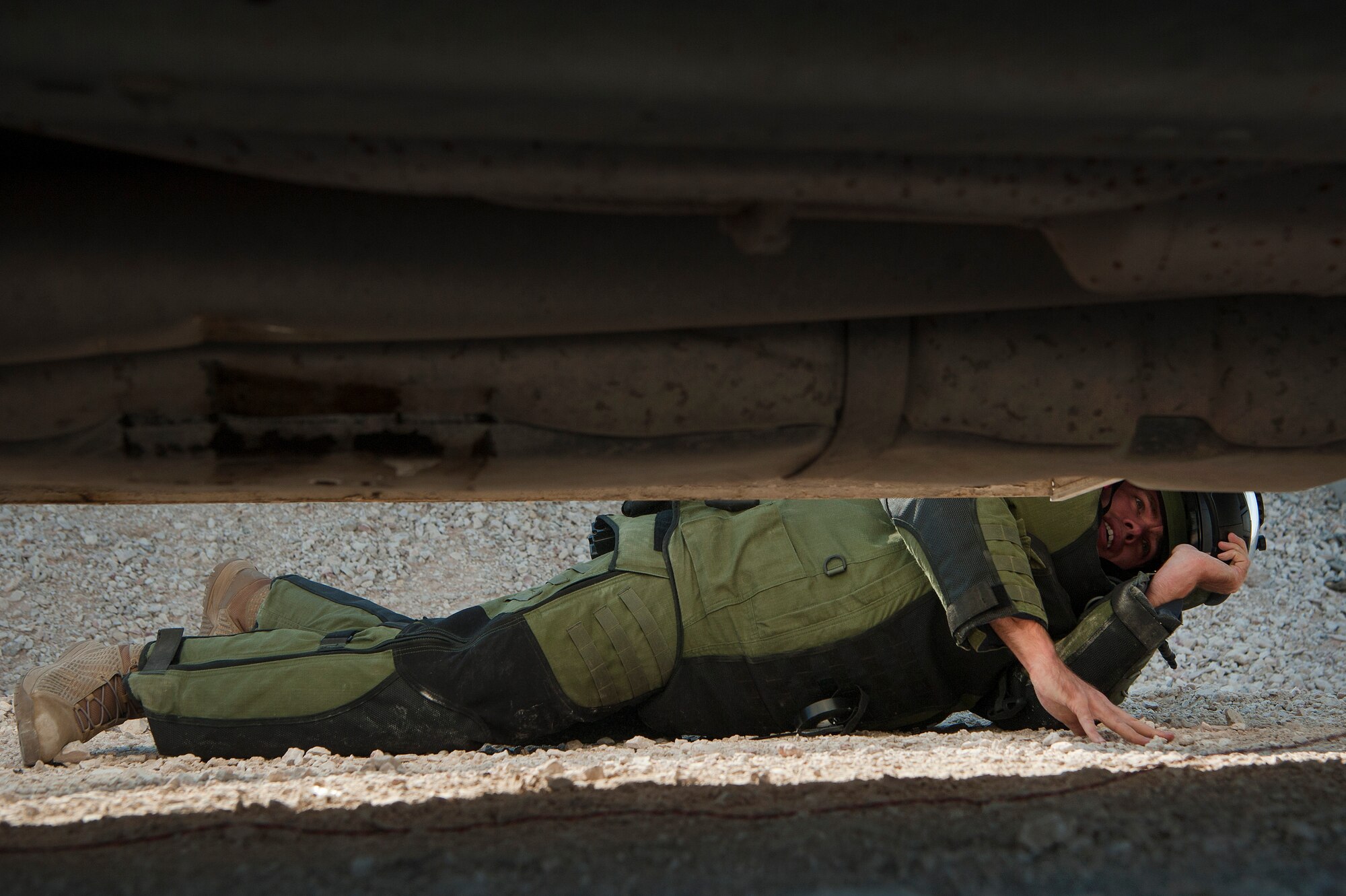 Tech. Sgt. Michael Case, 379th Expeditionary Civil Engineer Squadron explosive, ordnance, and disposal (EOD) team member, searches under a vehicle while suited in an EOD 10 Bomb Suit, during a vehicle borne improvised explosive device (VBIED) response training exercise Dec. 18, 2018, at Al Udeid Air Base, Qatar. Training participants utilized an F6A robotic platform, the bomb suit, and other specific tools to disrupt a VBIED during the exercise. (U.S. Air Force photo by Tech. Sgt. Christopher Hubenthal)