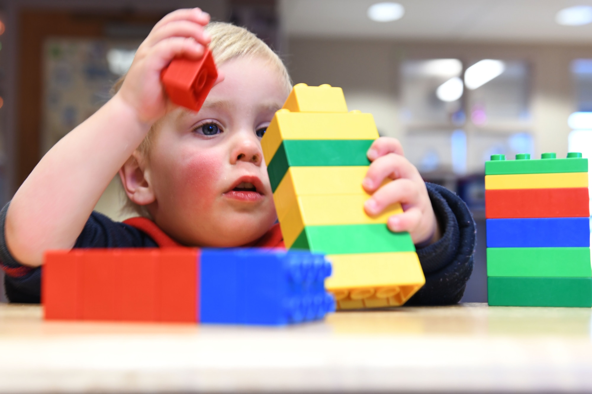 Jackson Scott, the son of Staff Sgt. Matthew Scott a 372nd Training Squadron professional military education instructor, creates a block tower at the McRaven Child Development Center on Ellsworth Air Force Base, S.D., Dec. 6, 2018. Playing with building blocks promotes hand-eye coordination, motor skills and color recognition in young children. (U.S. Air Force photo by Airman 1st Class Christina Bennett)