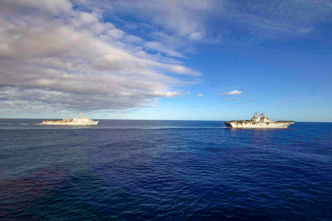 Two naval ships travel in formation across the open ocean.