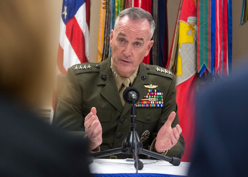 Marine Corps Gen. Joe Dunford speaks into a microphone  while sitting at a table.