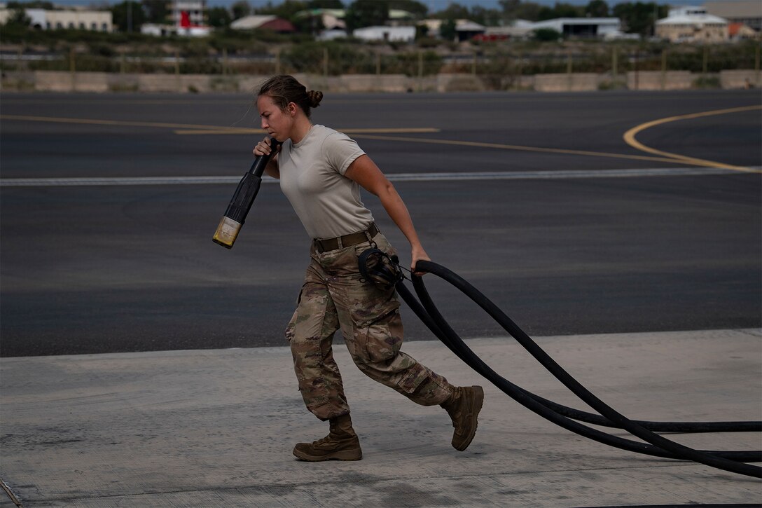 A service member carries a power cable.