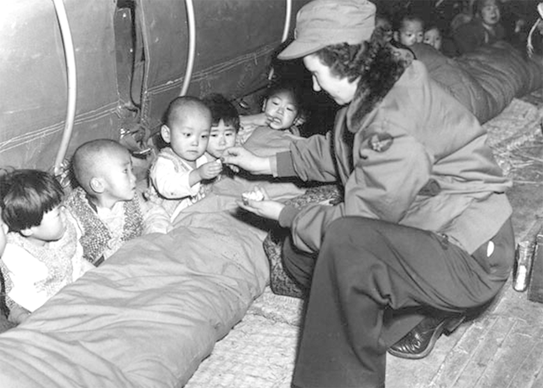 U.S. Air Force Capt. Mary Spivak, a flight nurse, hands out candy to orphans during Operation Chirstmas Kidlift. Almost 1,000 orphans from Seoul were evacuated by air before the Chinese Army retook the city. (U.S. Air Force photo)