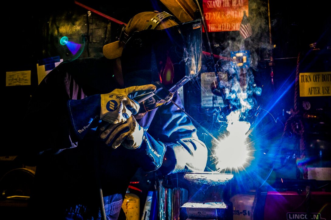 A sailor welds a pipe.