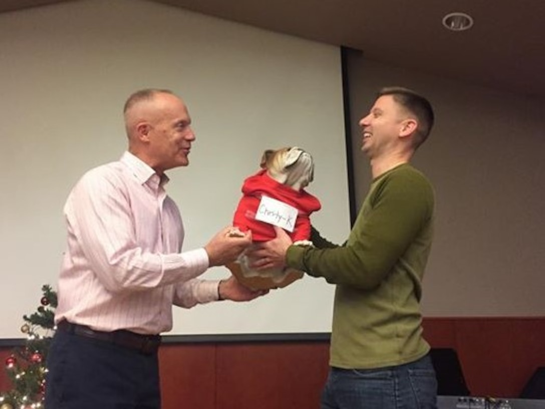 CAMP HUMPHREYS, Republic of Korea – Maj. Gen. Patrick J. Hermesmann, commander of U.S. Marine Corps Forces Korea, awards the Chesty-K, the official mascot of MARFORK, to Maj. Benjamin P. Neff, G6 deputy officer-in-charge, as well as his COMMSOX team comprised of all G6 Marines during the MARFORK Holiday Party here, Dec. 21. The MARFORK Marines compete for the right to custody of Chesty-K at unit events.  Marines and families used the Pacific Victors Chapel for the holiday party to celebrate the command’s accomplishments, strengthen relationships within the command, and share their common fellowship with each other.