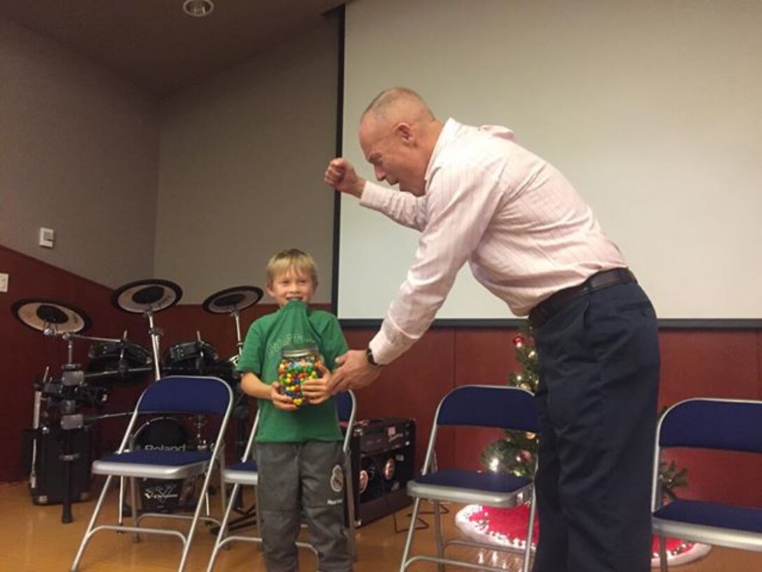 CAMP HUMPHREYS, Republic of Korea – Maj. Gen. Patrick J. Hermesmann, commander of U.S. Marine Corps Forces Korea, awards Gabe Neagle more than 1,300 pieces of candy after he came closest among nearly one hundred entries to guessing the correct count in the jar during the MARFORK Holiday Party here, Dec. 21.  Marines and families used the Pacific Victors Chapel for the holiday party to celebrate the command’s accomplishments, strengthen relationships within the command, and share their common fellowship with each other.