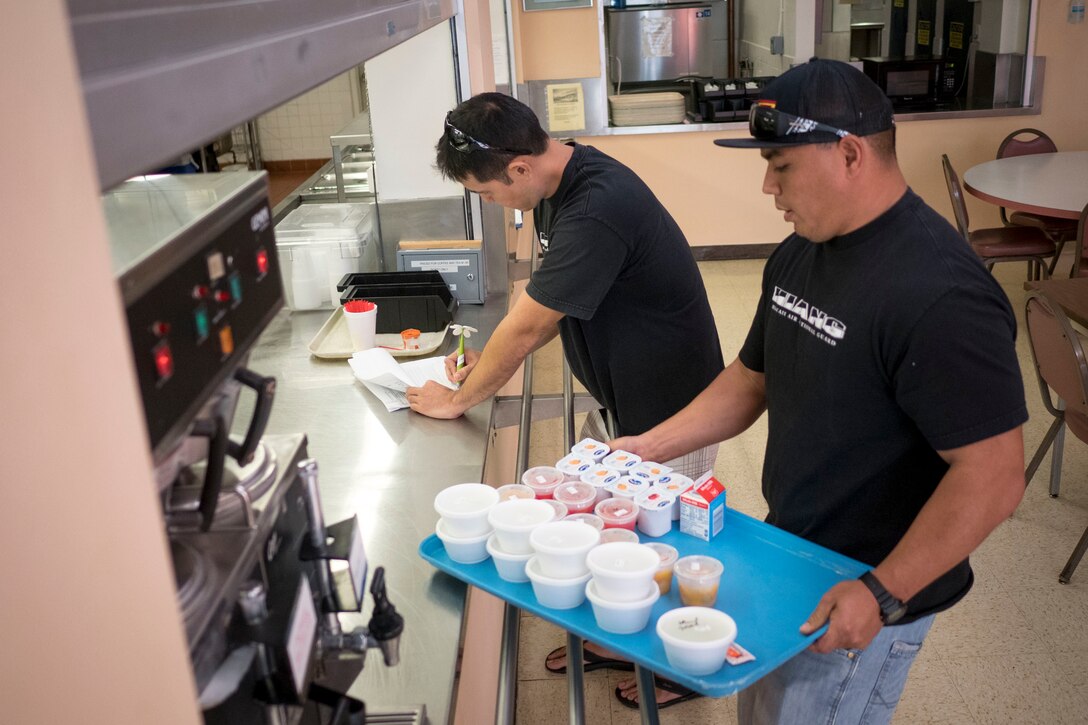 Tech. Sgt. Randall Kobayashi and Staff Sgt. John Quijano, from the Hawaii Air National Guard’s 154th Logistics Squadron, pick up meals Dec. 17, 2018