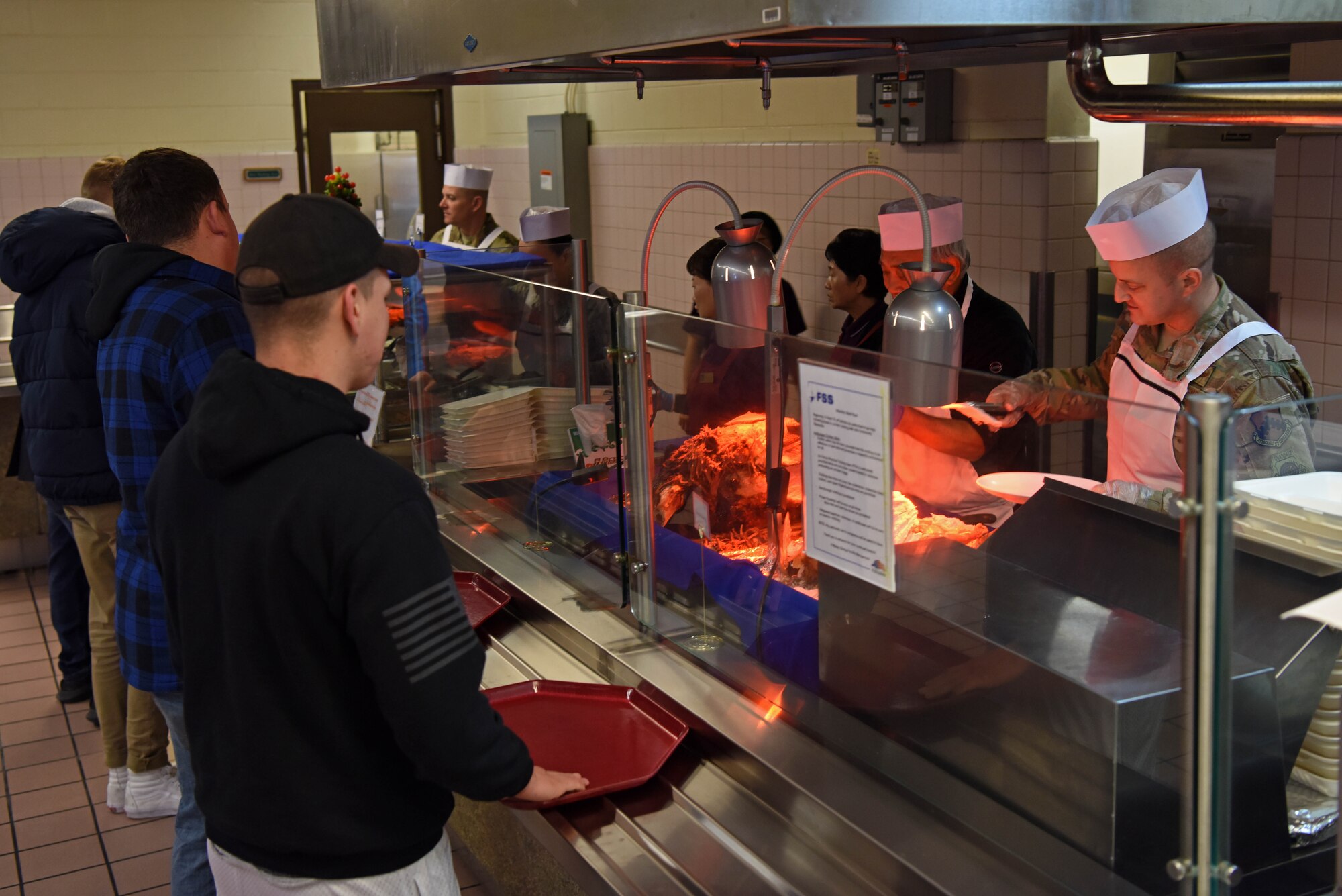 Leaders from the 8th Fighter Wing and dining facility workers provide holiday meals to service members at Kunsan Air Base, Republic of Korea, Dec. 25, 2018. Wing leadership served meals to help boost morale around the holidays. (U.S. Air Force photo by Staff Sgt. Joshua Edwards)