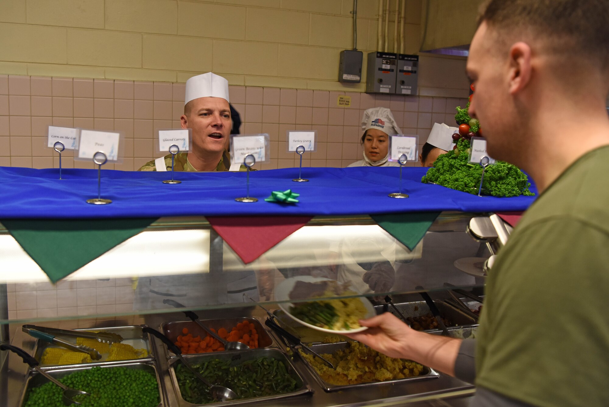 U.S. Air Force Chief Master Sgt. Michael Moore, 8th Fighter Wing command chief, wishes a Happy Holidays as he hands U.S. Army Sgt. Thomas Howard, Alpha Battery, 2nd Battalion of the 1st Air Defense Artillery operator, a holiday meal at Kunsan Air Base, Republic of Korea, Dec. 25, 2018. 8th Fighter Wing leadership served this meal to Airmen to help boost morale around the holidays. (U.S. Air Force photo by Staff Sgt. Joshua Edwards)