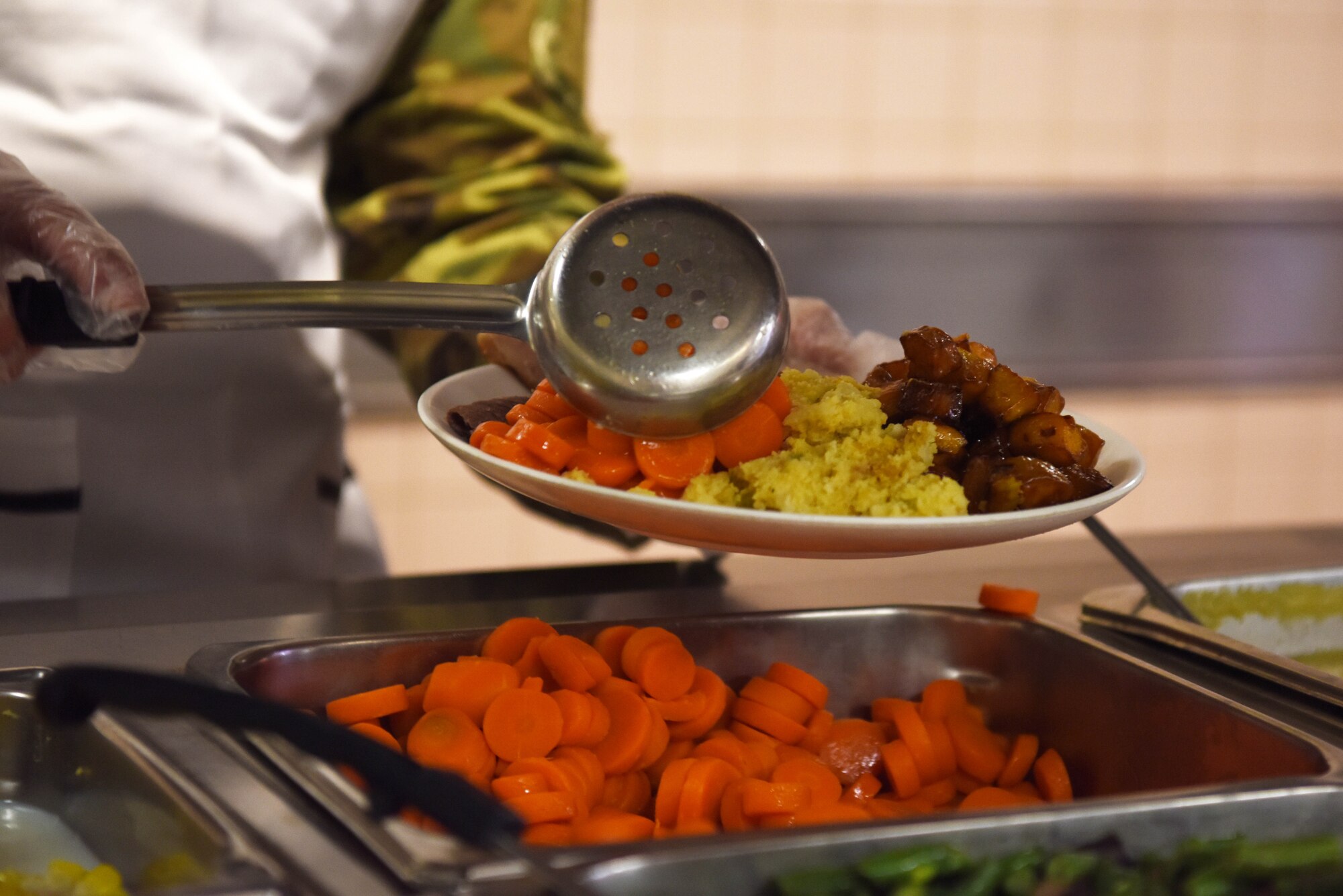 U.S. Air Force Chief Master Sgt. Michael Moore, 8th Fighter Wing command chief, plates carrots during a holiday meal at Kunsan Air Base, Republic of Korea, Dec. 25, 2018. 8th Fighter Wing leadership served this meal to Airmen to help boost morale around the holidays. (U.S. Air Force photo by Staff Sgt. Joshua Edwards)
