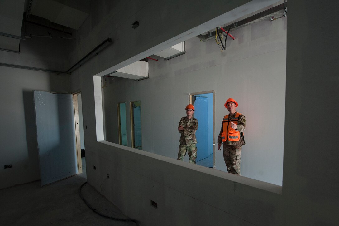 Senior Airman Stephan Giorgio, left, 379th Expeditionary Contracting Squadron contingency contracting officer, and Tech. Sgt. Jesse Gent, right, 379th Expeditionary Civil Engineer Squadron construction project manager, tour the progress of a construction project Dec. 17, 2018, at Al Udeid Air Base, Qatar. One of Giorgio’s four contracts is the $3.5 million North Squadron Complex contract that includes the construction of four buildings designed to house units in the future. By utilizing their capability to award contracts and procure funding, contracting officers enable a diverse range of projects at Al Udeid including construction, services, commodities and programs. (U.S. Air Force photo by Tech. Sgt. Christopher Hubenthal)