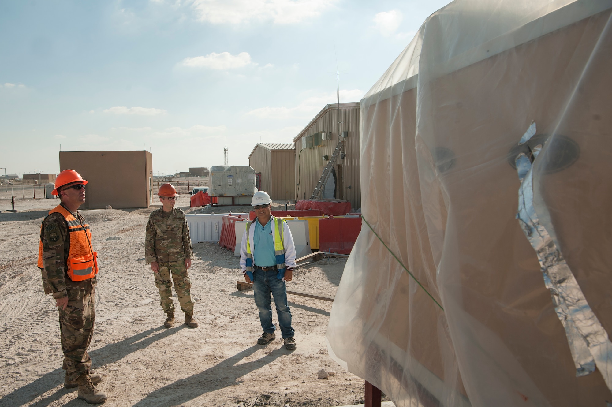 Senior Airman Stephan Giorgio, center, 379th Expeditionary Contracting Squadron contingency contracting officer, talks with Tech. Sgt. Jesse Gent, left, 379th Expeditionary Civil Engineer Squadron construction project manager, and Reymundo Balingit Camiling, Q-Pro Trading and Contracting site manager, during a tour of a construction project Dec. 17, 2018, at Al Udeid Air Base, Qatar. One of Giorgio’s four contracts is the $3.5 million North Squadron Complex contract that includes the construction of four buildings designed to house units in the future. By utilizing their capability to award contracts and procure funding, contracting officers enable a diverse range of projects at Al Udeid including construction, services, commodities and programs. (U.S. Air Force photo by Tech. Sgt. Christopher Hubenthal)