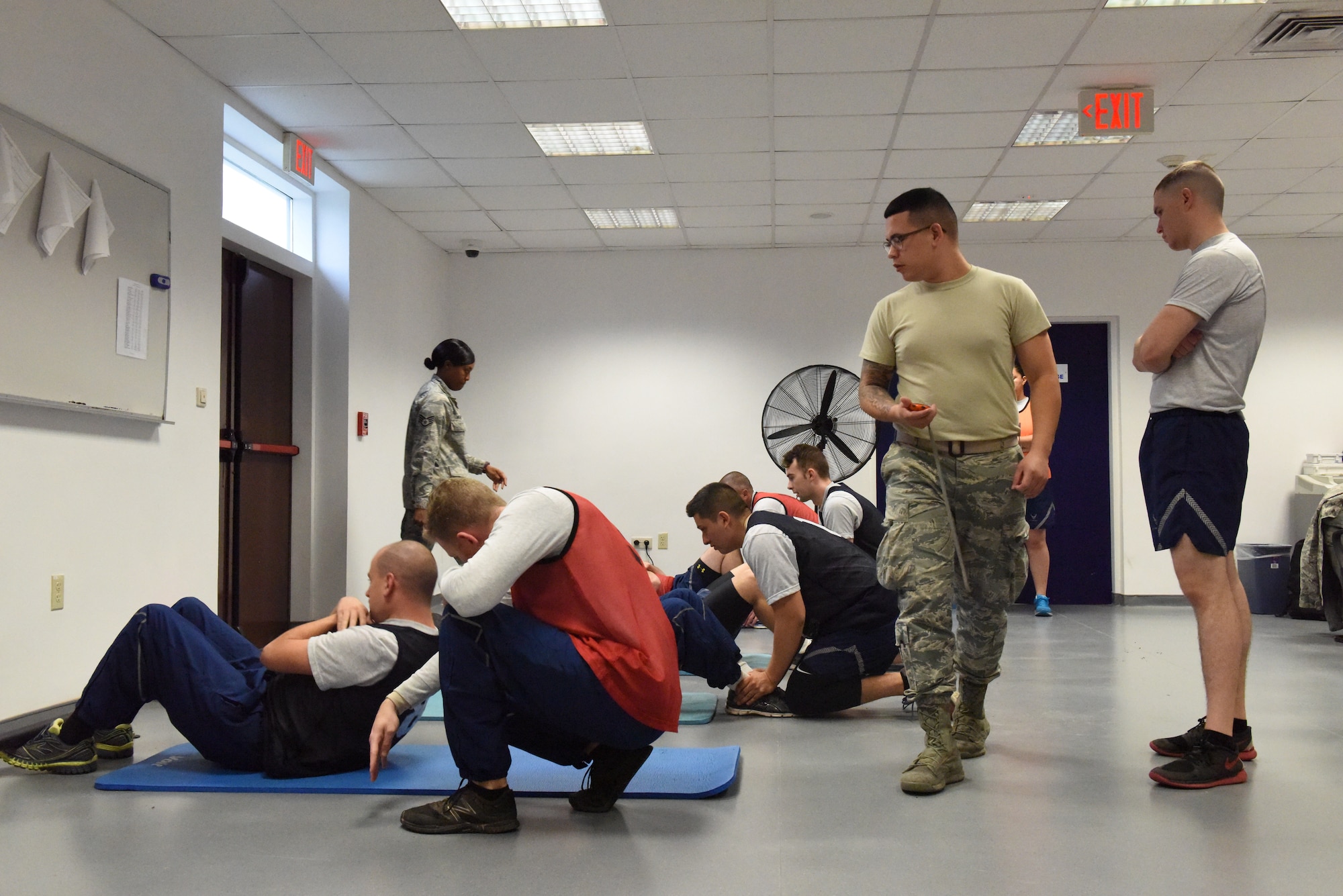 A fitness specialist checks for proper form as service members perform their fitness test.